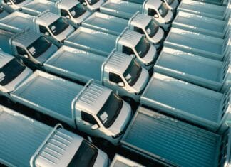 Duża flota białych pickupów zaparkowanych w równych rzędach z lotu ptaka