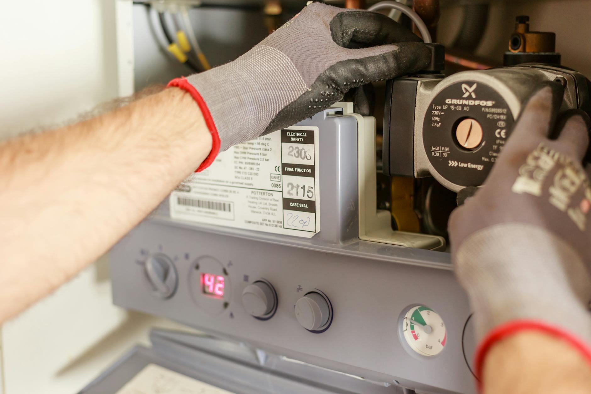 Dłonie instalatora regulujące parametry energooszczędnego kotła gazowego