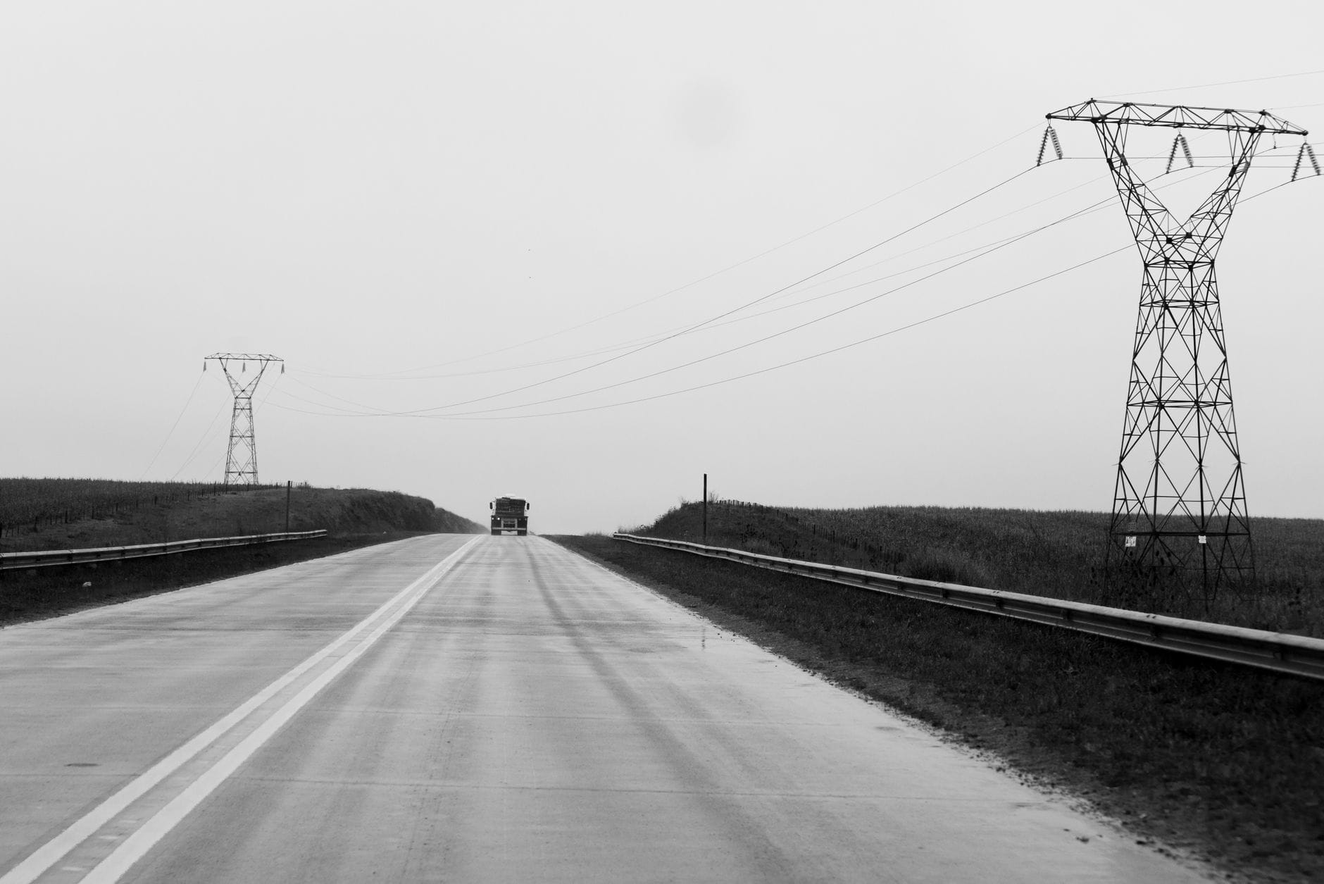 Pustka na szosie z liniami energetycznymi i odległą ciężarówką