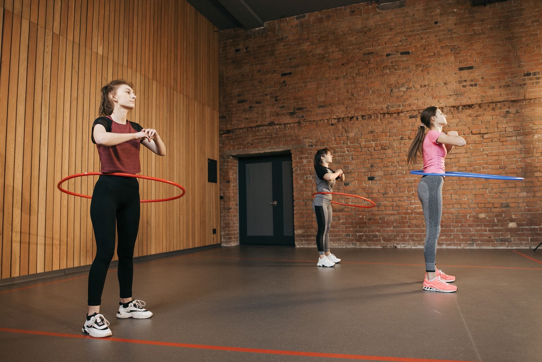 Trzy kobiety ćwiczą z kołami hula hoop w sali fitness