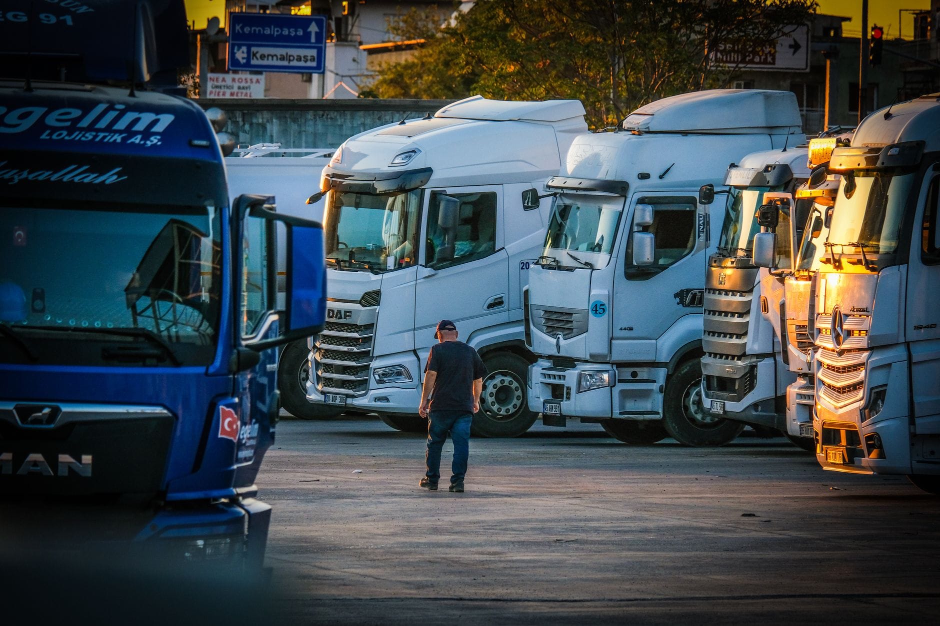 Mężczyzna idzie między zaparkowanymi ciężarówkami o zachodzie słońca